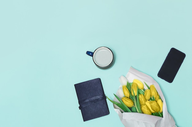 Coffee cup, spring tulip flowers on table