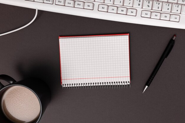 Coffee Cup Standing on Desk Important infrormation written on paper Different Office Supplies Pencils Pens Marckers Computer keyboard Text on wood table