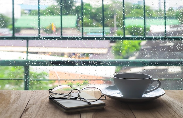 Coffee cup on table by window during rainy season
