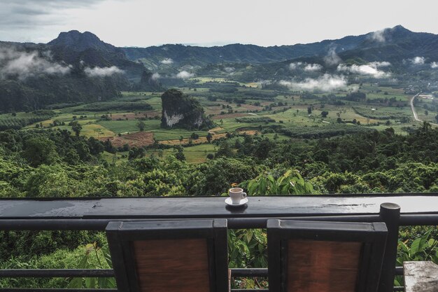 背景として朝の山の景色を望むテーブルの上のコーヒーカップ