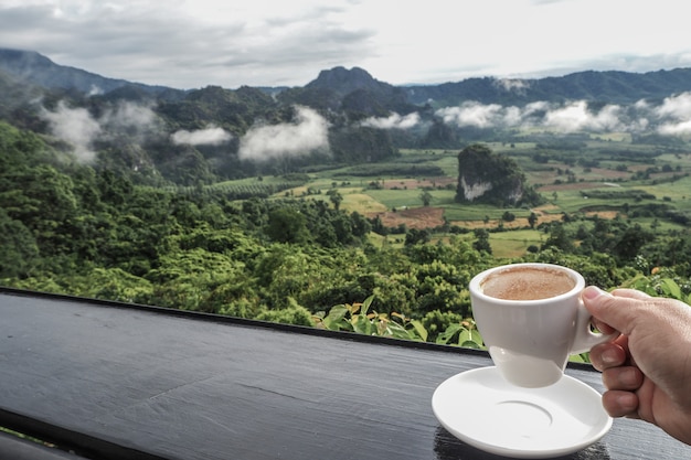 背景として朝の山の景色を望むテーブルの上のコーヒーカップ