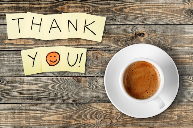 Coffee cup and thank you note   on wooden background