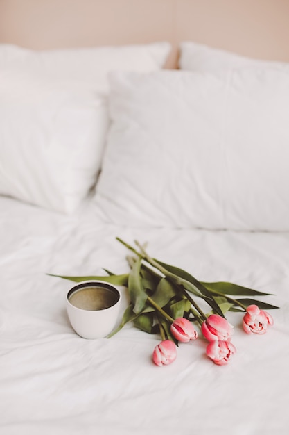 Coffee cup and tulips in bed.