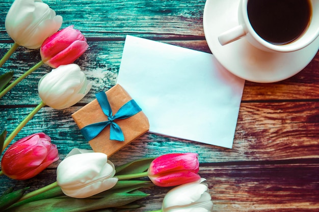 Coffee cup and tulips on wooden background