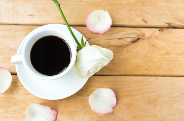 Coffee cup and white rose on wooden background Love concept Flat lay top view