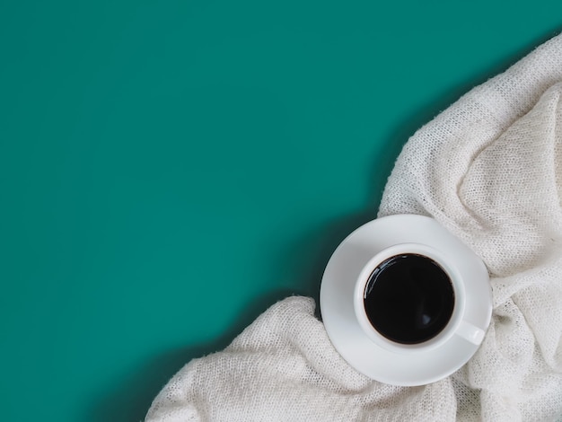 A coffee cup and white sweater on green background