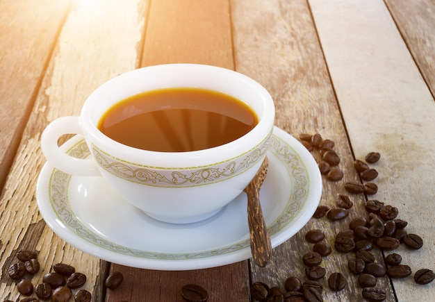 Coffee cup with burlap sack of coffee beans on wooden table