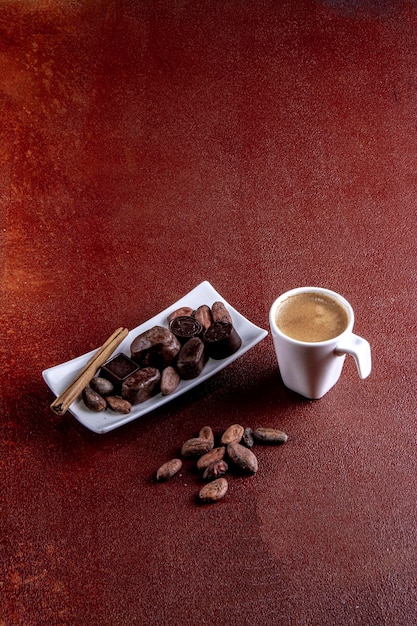 Coffee cup with chocolates photographed on brown painted background