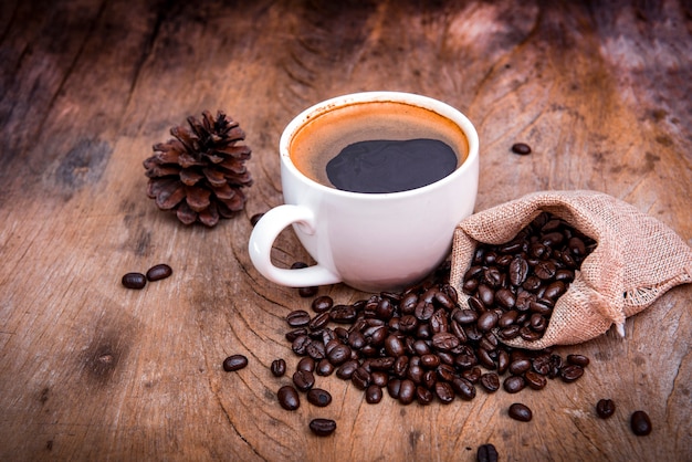 木製の背景にコーヒー豆とコーヒーカップ