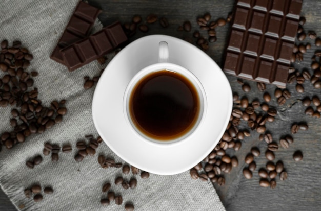 Coffee cup with cookies and chocolate with scattered coffee beans wooden table Mug of coffee