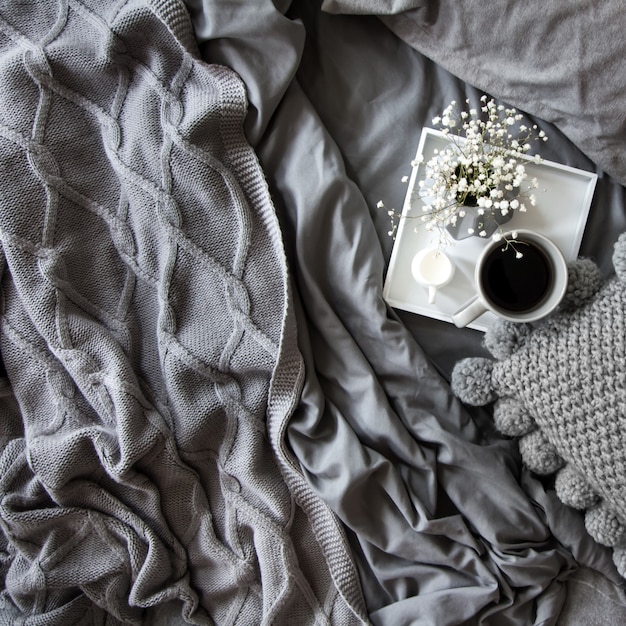 Coffee cup with milk and flowers on a tray in bed