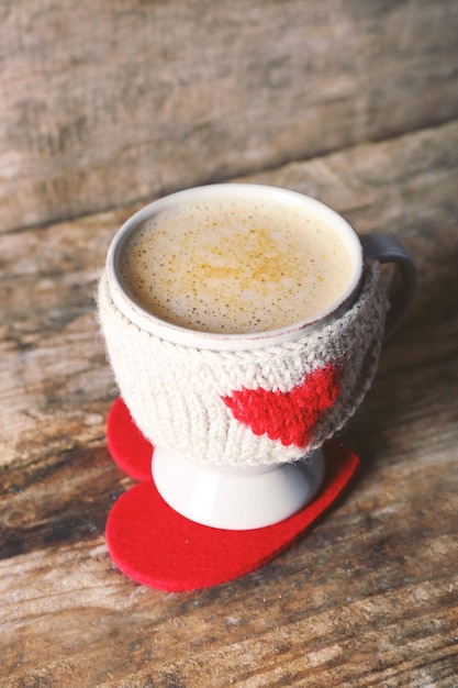 Coffee cup with milk on a stand heart on wooden table