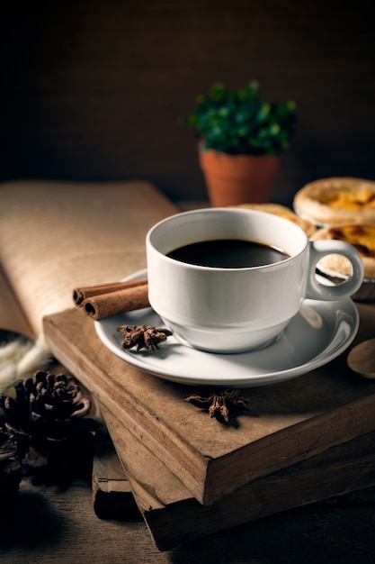 Coffee cup with old book on rustic wooden table, classic concept.