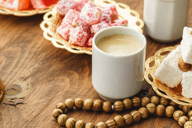 Coffee cup with oriental sweets on wooden table close up