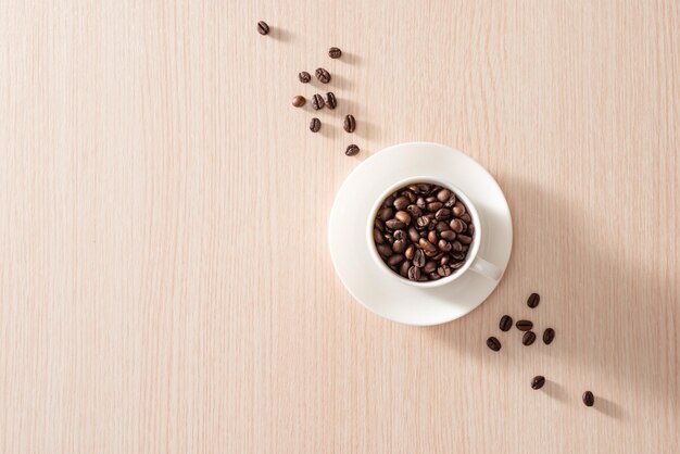 Coffee cup with roasted beans on wood background