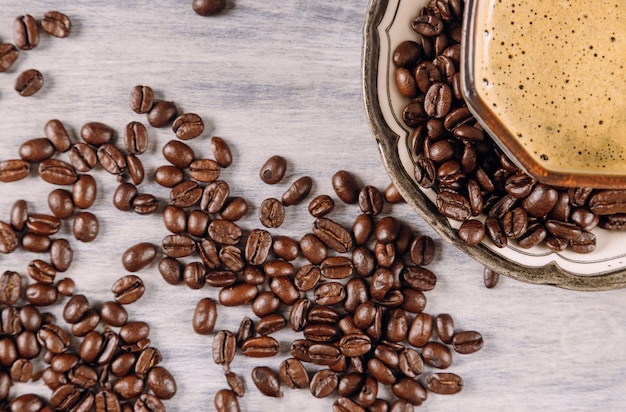 Tazza di caffè con chicchi di caffè tostati intorno