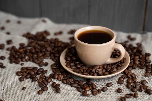 Coffee cup with roasted coffee beans on linen background Mug of black coffe