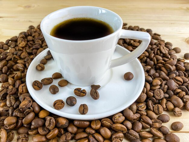 Coffee in a cup with a saucer and coffee grains on a wooden table