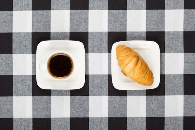 Coffee cup with saucer and croissant