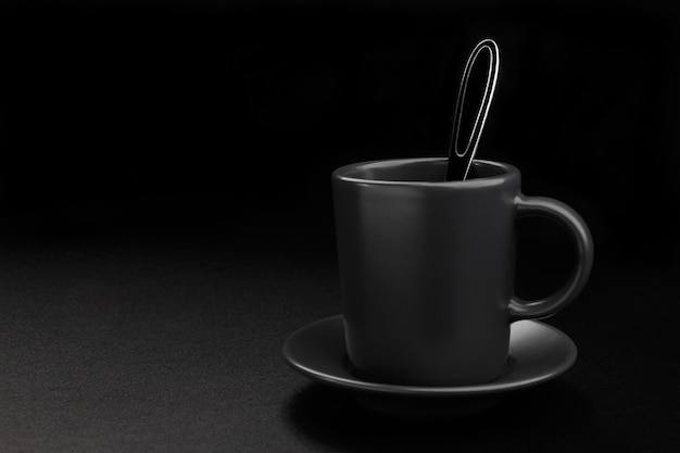 Foto tazza di caffè con cucchiaio su sfondo nero