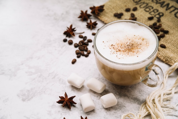 Foto tazza di caffè con anice stellato; marshmallow; e chicchi di caffè su sfondo bianco