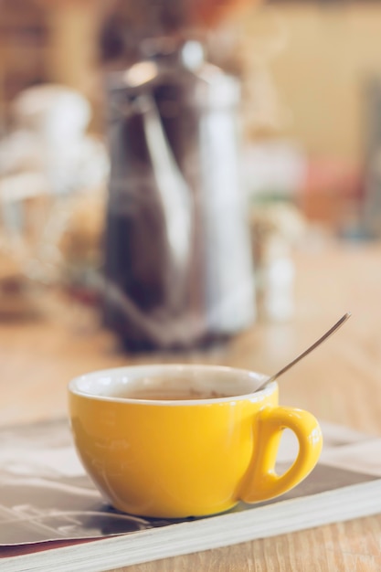 Coffee cup with steam on wood table in cafe