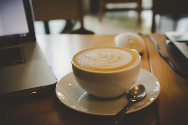 朝の木のテーブルの上のコーヒーカップ