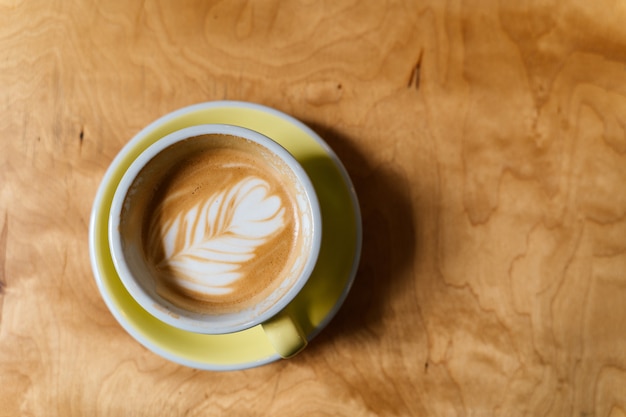 Photo coffee cup on wood table top view. alternative milk. wooden midcentury background. foam art