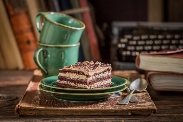 Coffee cups and chocolate cake on writer desk