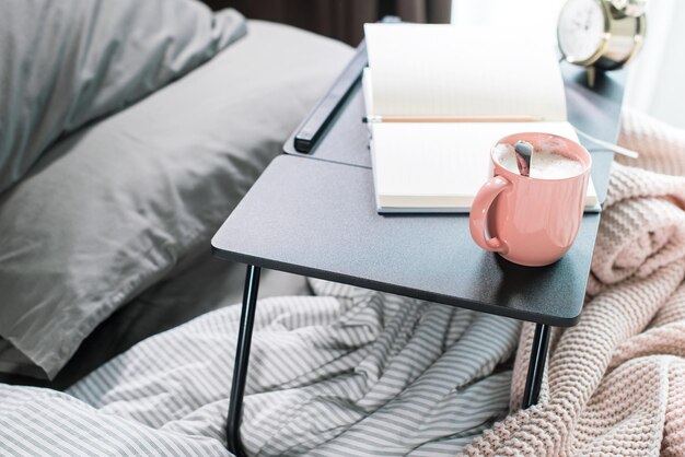 Coffee daily pencil on table on cosy grey bed and pink plaid for woman to plan day early morning