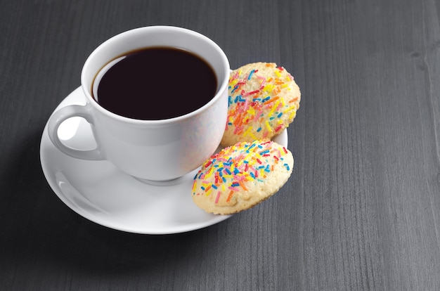 Coffee and delicious cookies on black wooden table