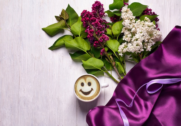 Coffee and different lilac flowers on white background