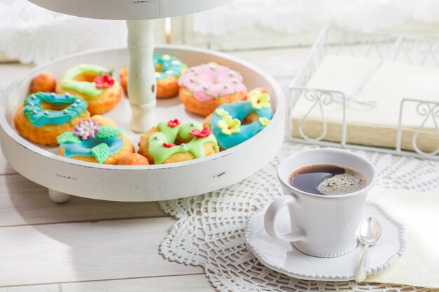 Coffee and donuts with colorful decoration on white table