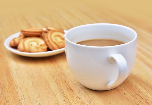 コーヒーはコーヒータイムのクッキーと木製のテーブルの上