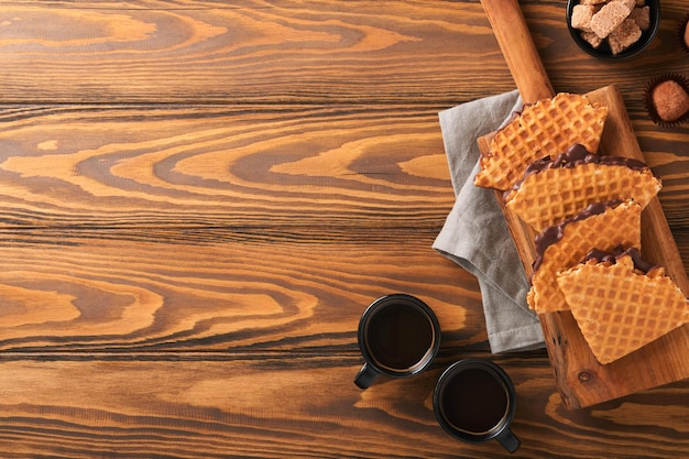 커피와 더치 와플 에스프레소 커피와 더치 와플 또는 시럽 와플 쿠키와 초콜릿을 오래된 나무 테이블에 올려 아침 식사를 위한 완벽한 시럽 와플 쿠키 탑 뷰 모의