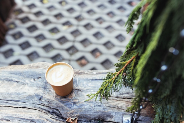 松の枝と秋または冬の庭で環境に優しい紙コップでコーヒー