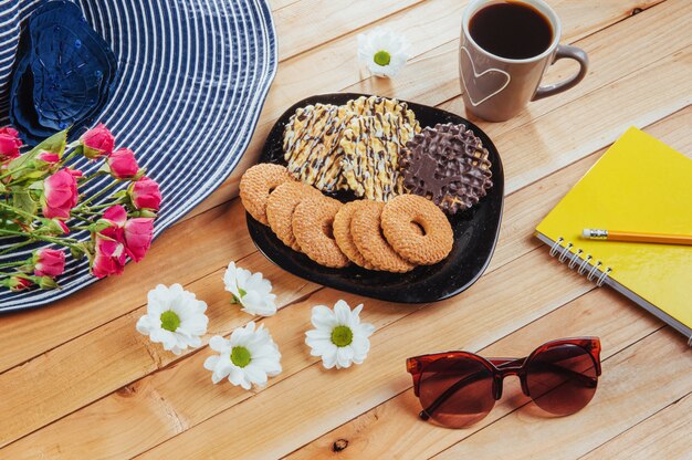 Coffee espresso stands on a wooden table with cookies, pad and pencil.