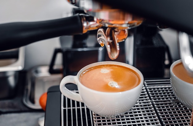 에스프레소 컵에 커피를 붓는 포터필터가 있는 커피 머신에서 커피 추출