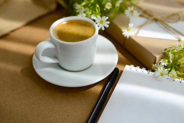 Coffee and flowers, gift box and blank note paper on a table, copy space, blurred background