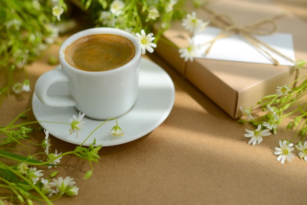 Coffee flowers and gift box with blank card soft focus blurred background Black coffee in white cup