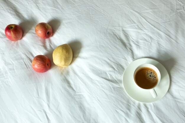 Coffee and fruits on white bed sheet
