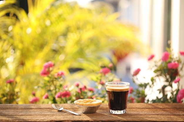 Photo coffee in a glass cup and egg tart and flower outdoor relaxing