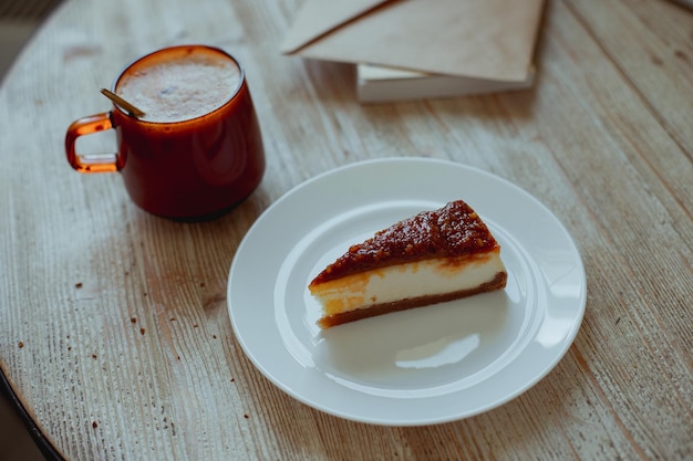 Coffee in a glass cup and nutty cheesecake on a white plate stand on a wooden table