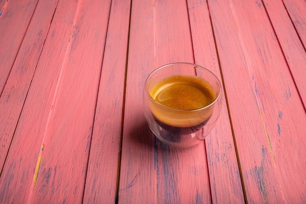 Foto caffè in tazza di vetro su fondo di legno rosa