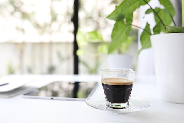 Coffee glass cup and tablet and plant pot on white desk