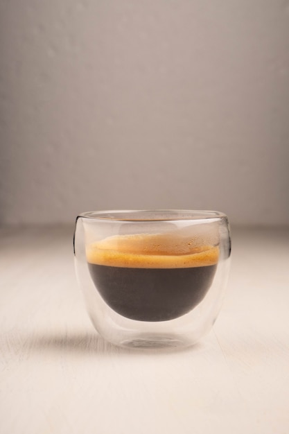 白い木製の背景の上のガラスカップのコーヒー