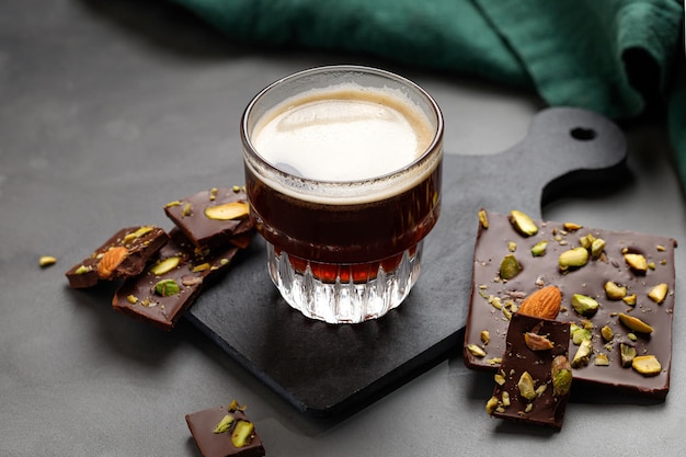 Coffee in glass with chocolate bar with almond pistachios dark\
sweet dessert with espresso