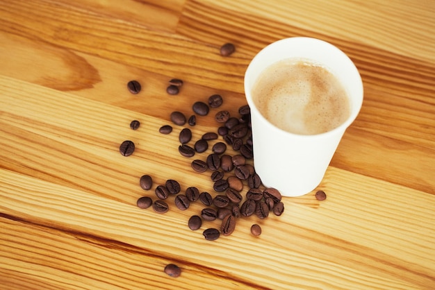 Coffee to go and beans on a wooden background