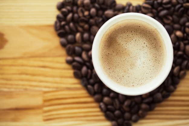 Coffee to go and beans on a wooden background