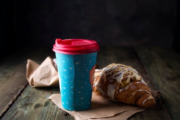 Coffee to go in a paper cup with croissants